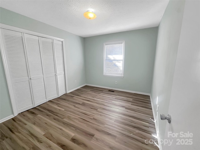 unfurnished bedroom with light hardwood / wood-style floors, a textured ceiling, and a closet