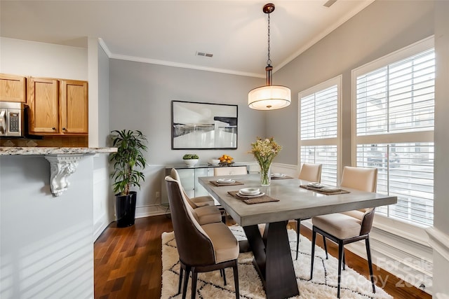 dining space with crown molding, a wealth of natural light, and dark wood-type flooring