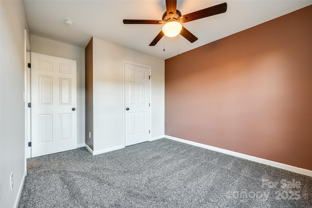 unfurnished bedroom with dark colored carpet, a closet, and ceiling fan