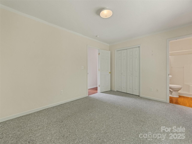 unfurnished bedroom with ensuite bathroom, carpet floors, crown molding, and a closet