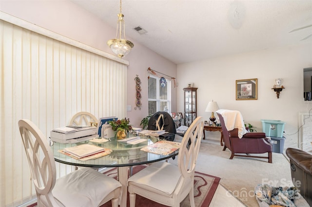 dining space with light colored carpet and a textured ceiling