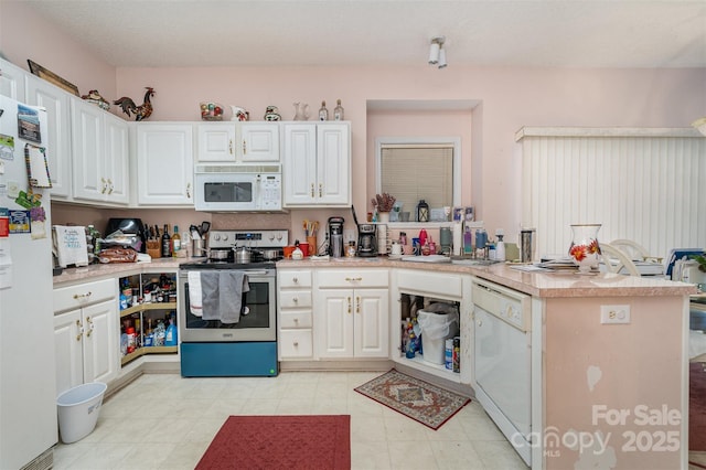 kitchen with a textured ceiling, kitchen peninsula, white cabinets, and white appliances