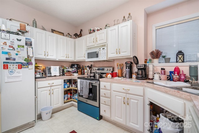 kitchen with white cabinets, a textured ceiling, white appliances, and sink