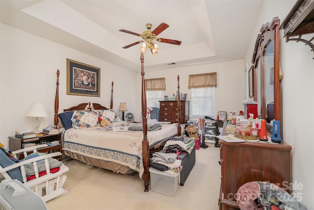 carpeted bedroom featuring a raised ceiling and ceiling fan