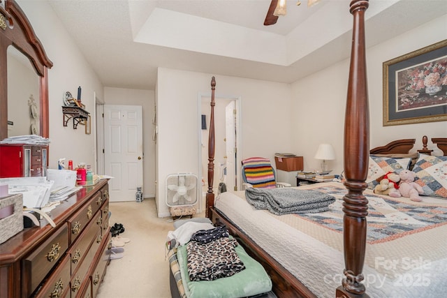 carpeted bedroom with ceiling fan and a tray ceiling