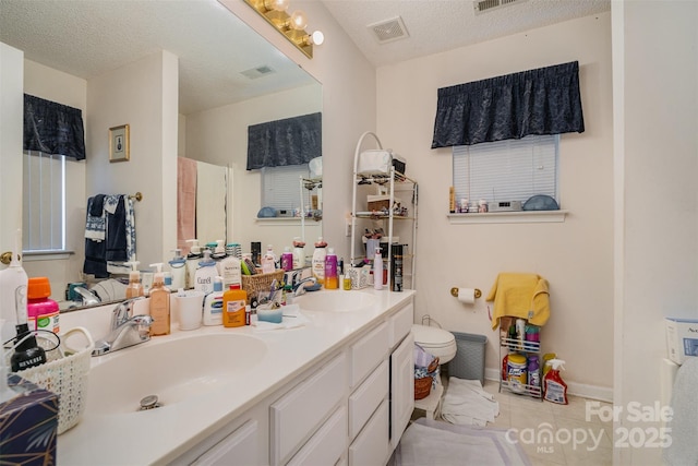 bathroom featuring tile patterned flooring, vanity, a textured ceiling, and toilet