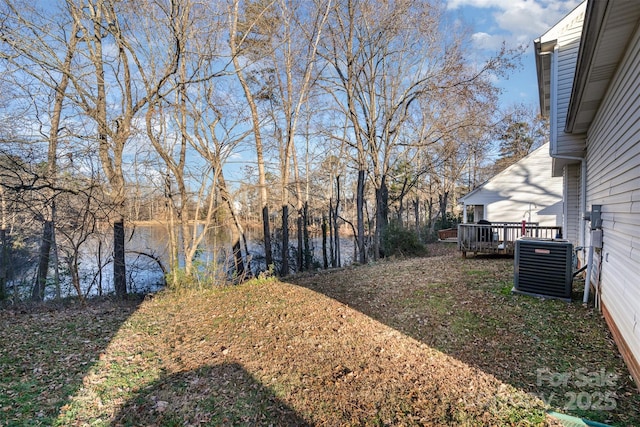 view of yard featuring a deck with water view and central AC unit