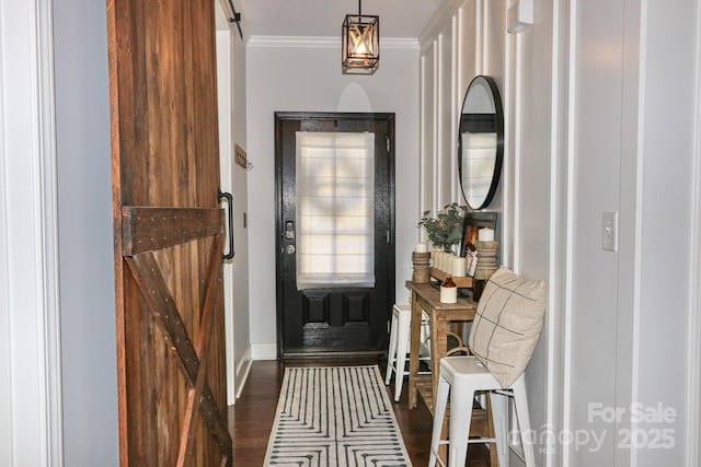 entryway with crown molding, a barn door, and dark wood-type flooring