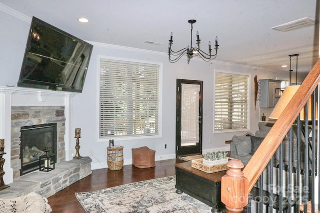 living room with a notable chandelier, a fireplace, ornamental molding, and dark hardwood / wood-style floors