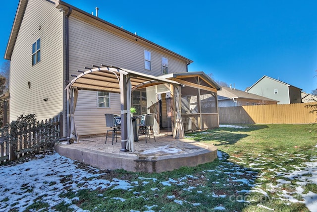 snow covered back of property with a patio and a lawn