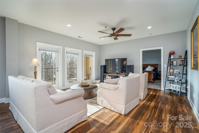 living room featuring dark wood-type flooring and ceiling fan