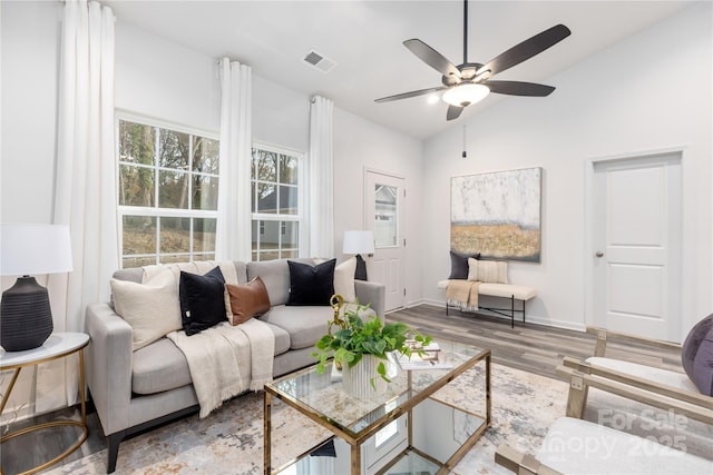 living room featuring ceiling fan, wood-type flooring, and vaulted ceiling