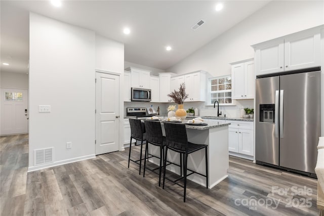 kitchen featuring white cabinets, sink, light stone countertops, a kitchen island, and stainless steel appliances