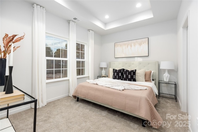 bedroom featuring light carpet and a tray ceiling