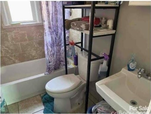 full bathroom featuring toilet, tile patterned floors, sink, and shower / bathtub combination with curtain