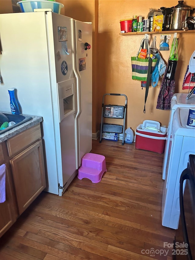 kitchen featuring washer / clothes dryer, dark hardwood / wood-style flooring, and white refrigerator with ice dispenser