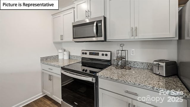 kitchen featuring white cabinets, appliances with stainless steel finishes, dark hardwood / wood-style flooring, and light stone countertops