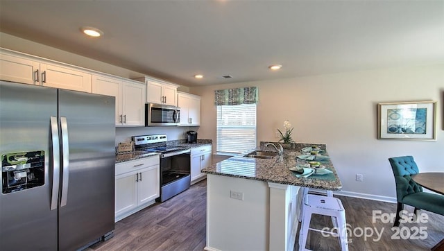 kitchen with dark stone counters, sink, white cabinets, and stainless steel appliances