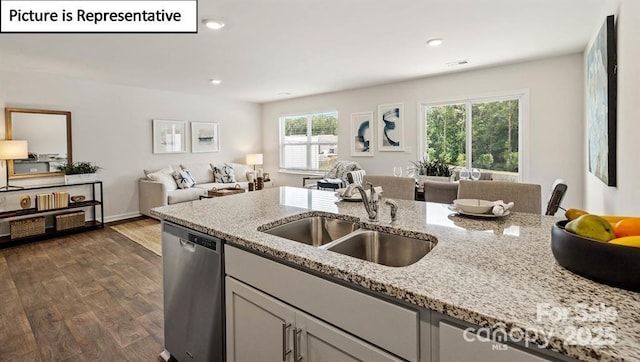 kitchen featuring stainless steel dishwasher, dark hardwood / wood-style floors, light stone countertops, and sink