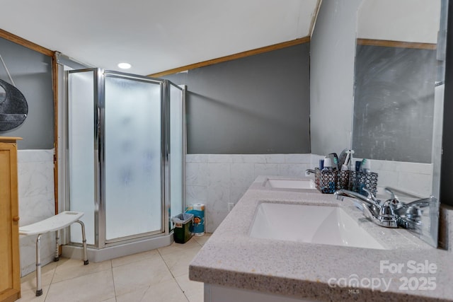 bathroom with tile patterned floors, vanity, a shower with shower door, and tile walls