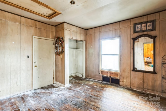 unfurnished bedroom featuring wood walls and a closet