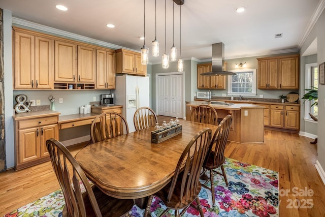 dining space with ornamental molding, sink, and light hardwood / wood-style flooring