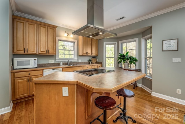 kitchen with a center island, sink, white appliances, island range hood, and a breakfast bar