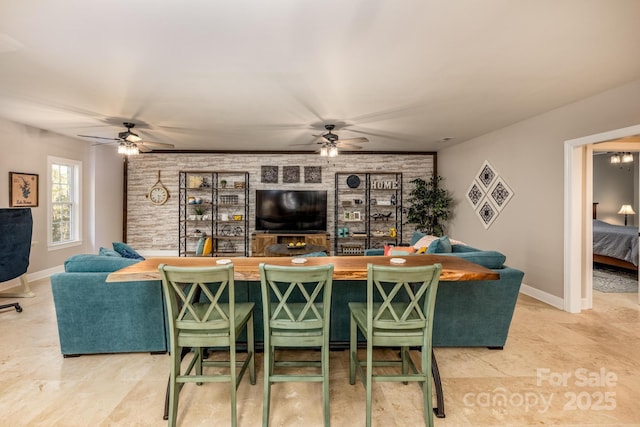 living room featuring bar area, ceiling fan, and brick wall