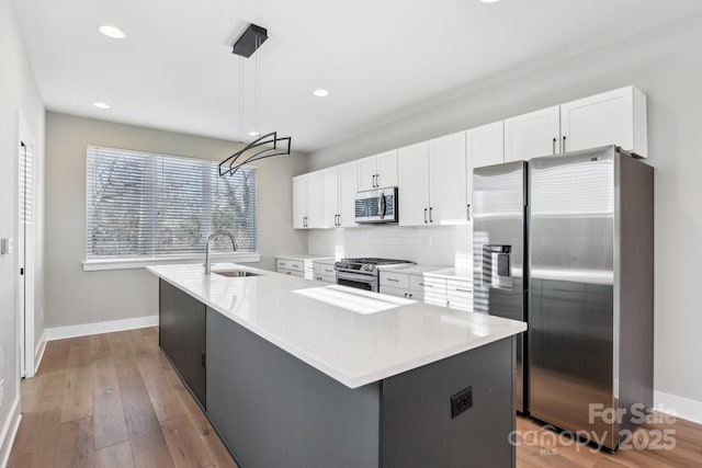 kitchen featuring stainless steel appliances, pendant lighting, an island with sink, and sink