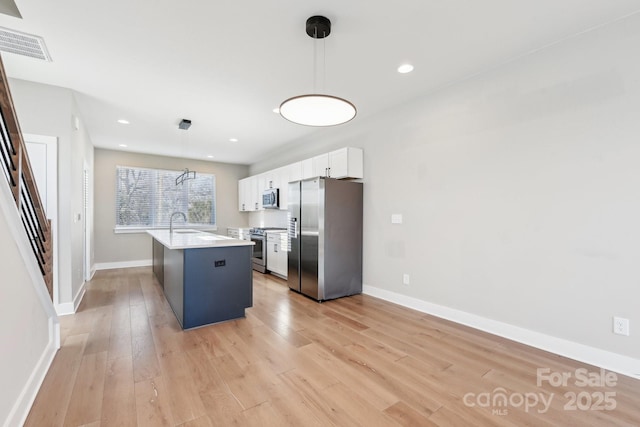 kitchen featuring white cabinetry, stainless steel appliances, a kitchen island, light hardwood / wood-style flooring, and decorative light fixtures