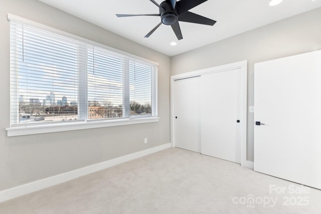 unfurnished bedroom featuring light carpet, a closet, and ceiling fan