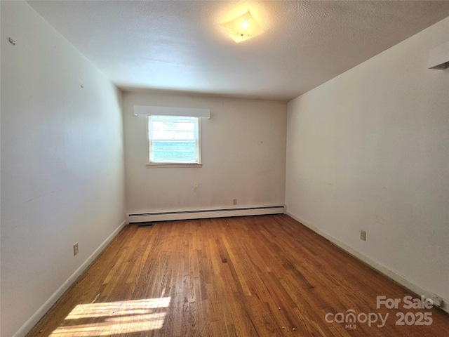 empty room featuring hardwood / wood-style floors, a textured ceiling, and a baseboard radiator