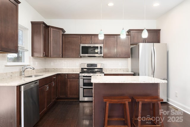 kitchen featuring hanging light fixtures, appliances with stainless steel finishes, sink, and dark wood-type flooring