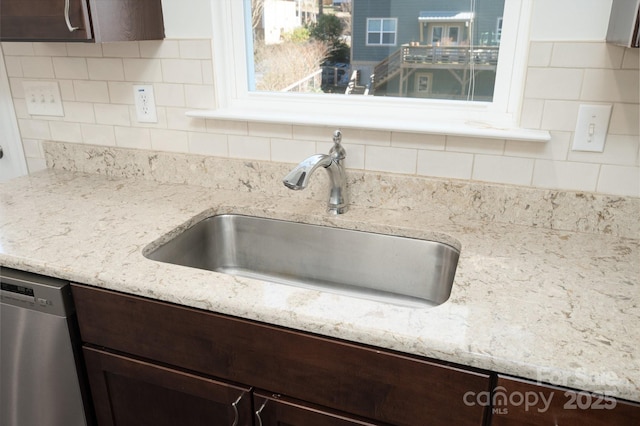 interior details with backsplash, sink, dark brown cabinetry, and stainless steel dishwasher