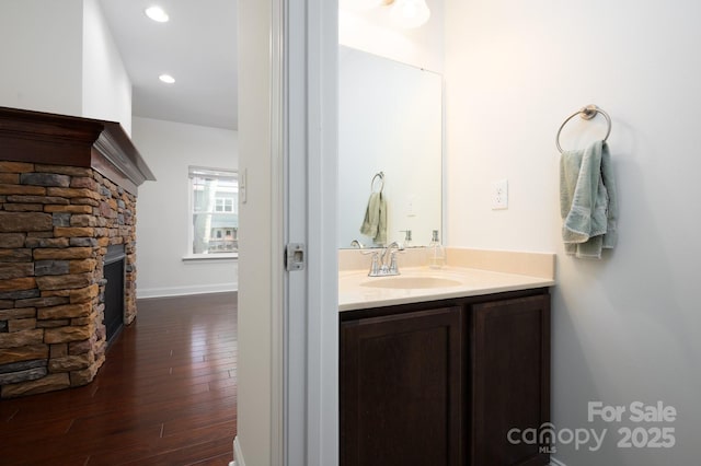 bathroom featuring vanity, a stone fireplace, and hardwood / wood-style flooring