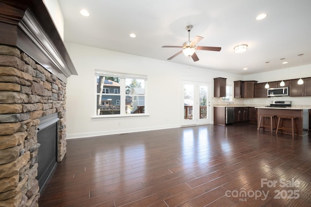 unfurnished living room featuring ceiling fan, a fireplace, and dark hardwood / wood-style floors