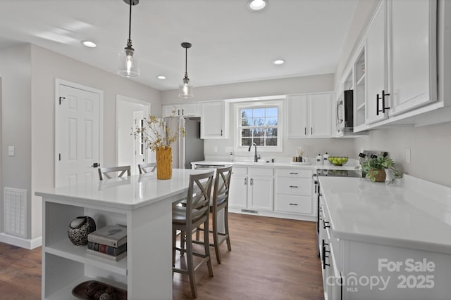 kitchen with a center island, white cabinets, sink, hanging light fixtures, and appliances with stainless steel finishes