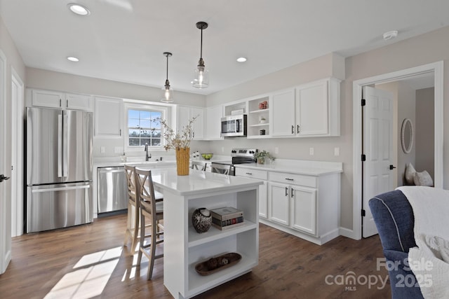 kitchen with pendant lighting, a center island, sink, white cabinetry, and stainless steel appliances