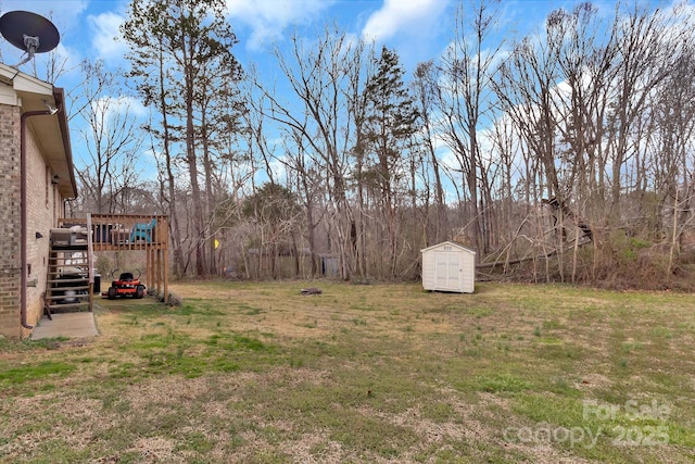 view of yard with a storage shed, a deck, an outbuilding, and stairs