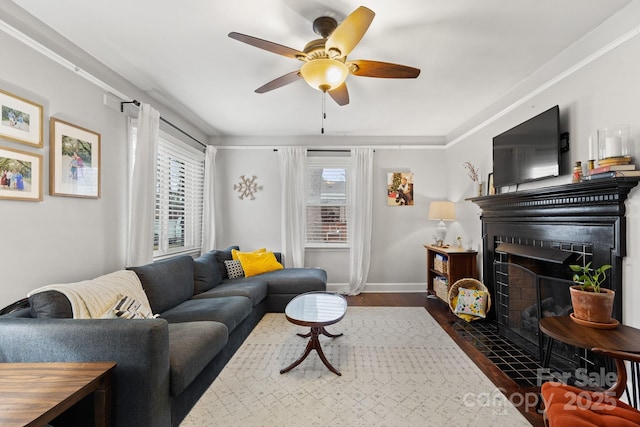 living room featuring plenty of natural light, ceiling fan, crown molding, and dark wood-type flooring