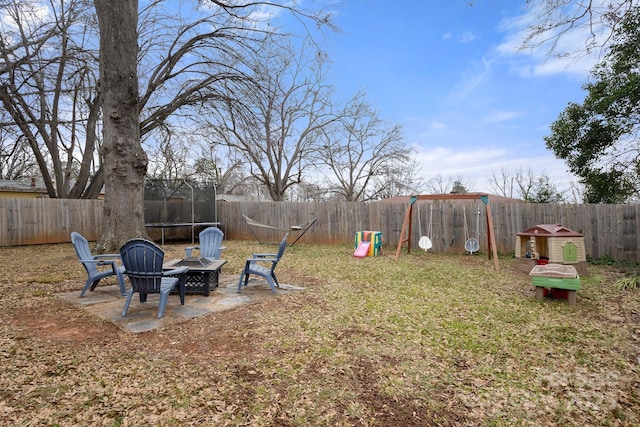 view of yard featuring a patio, a fire pit, and a trampoline