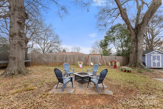 view of yard featuring an outdoor fire pit, a trampoline, a playground, a shed, and a patio