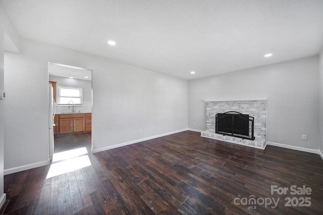 unfurnished living room featuring a fireplace, dark hardwood / wood-style floors, and sink