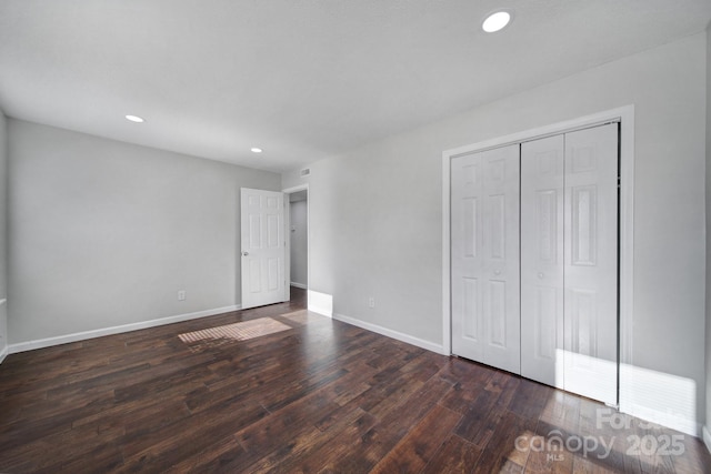 unfurnished bedroom with a closet and dark wood-type flooring