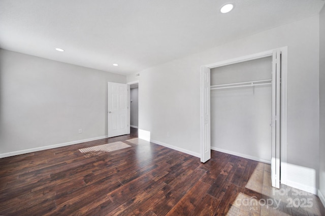 unfurnished bedroom featuring dark hardwood / wood-style flooring and a closet