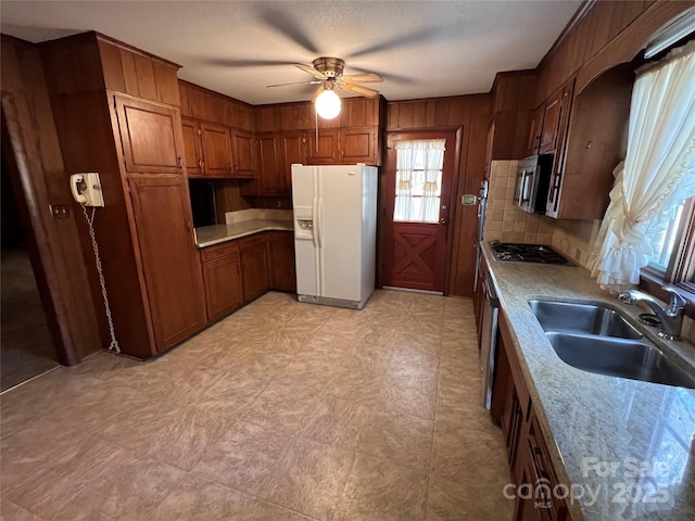 kitchen featuring appliances with stainless steel finishes, light stone counters, ceiling fan, and sink