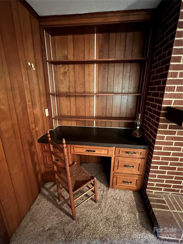 office area featuring carpet, built in desk, and wooden walls