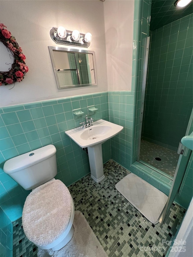 bathroom with tile patterned floors, toilet, an enclosed shower, and tile walls