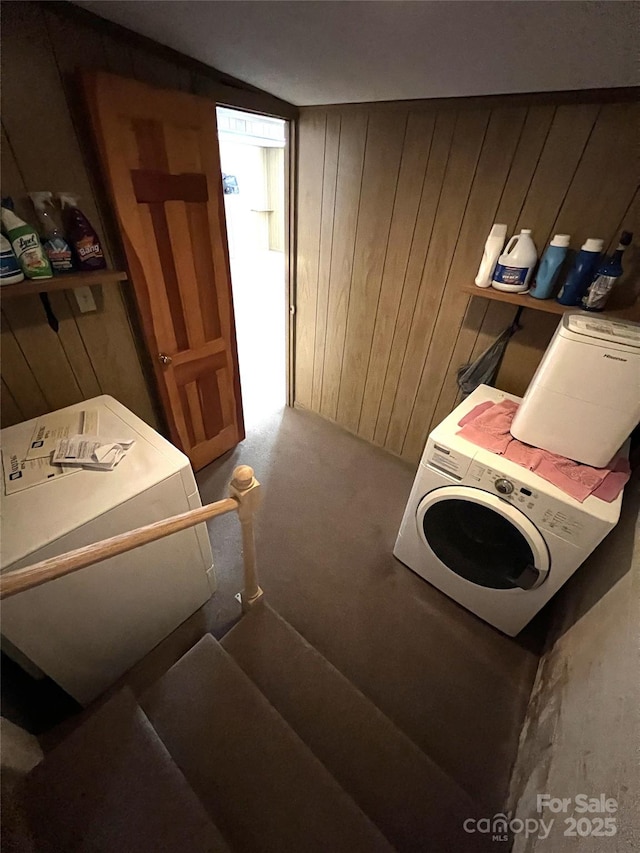 clothes washing area featuring separate washer and dryer and wood walls