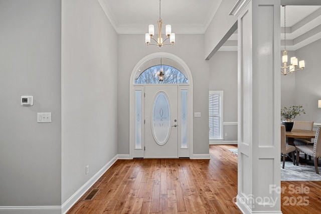 entrance foyer featuring an inviting chandelier, crown molding, and hardwood / wood-style floors